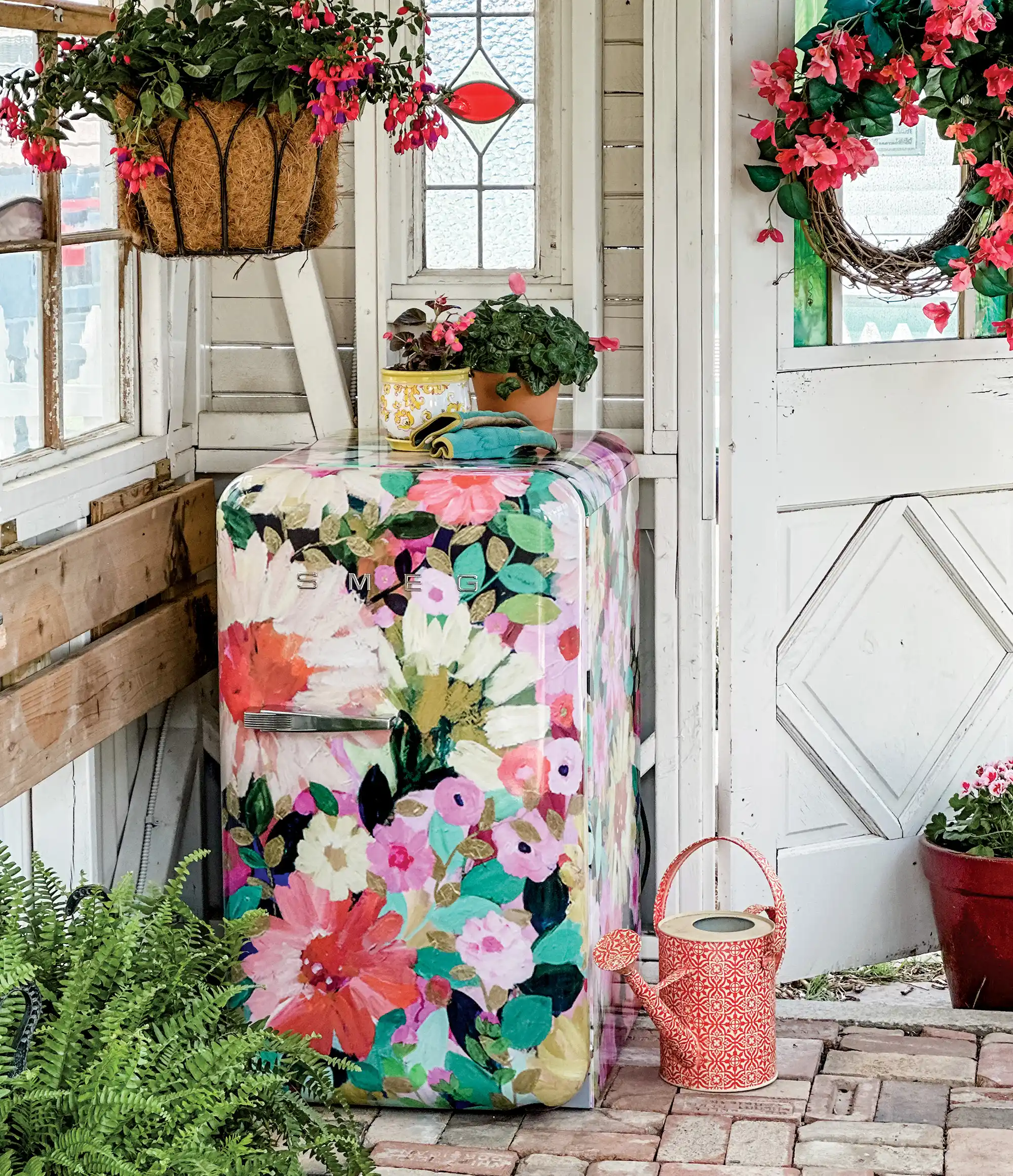 SMEG Floral refrigerator in garden with hanging flowers and watering can
